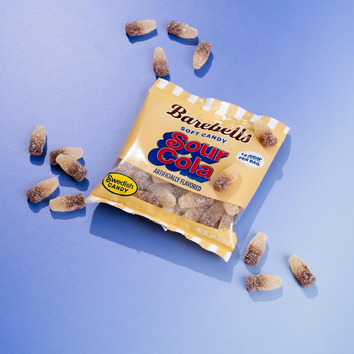 Barebells Soft Candy Sour Cola bag with sugar-coated cola bottle gummies on a blue background
