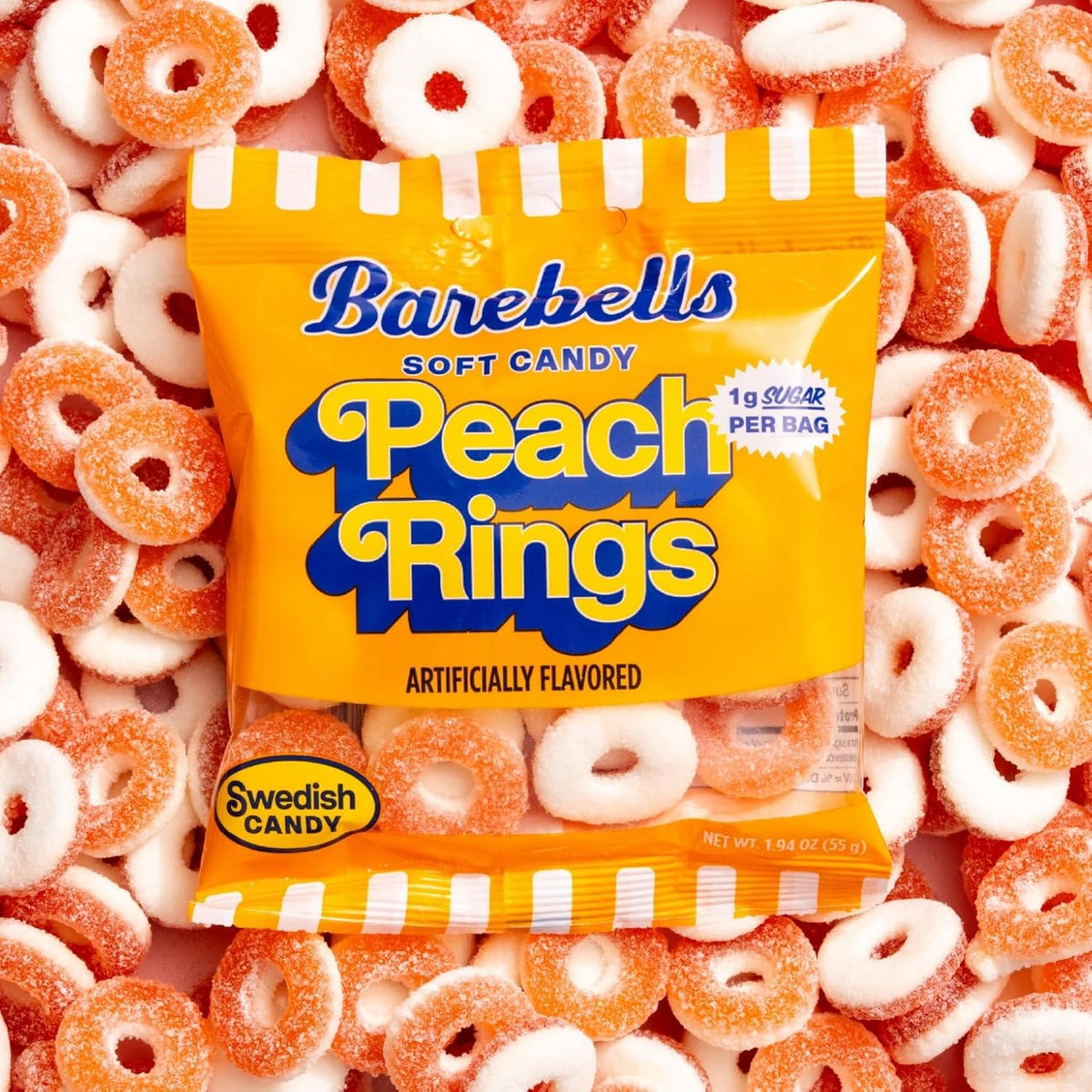 Barebells Soft Candy Peach Rings gummy bag resting on a pile of sugar-coated peach ring candies