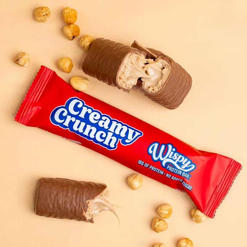Wispy Creamy Crunch protein bar wrapper with cut pieces and hazelnuts showing soft center