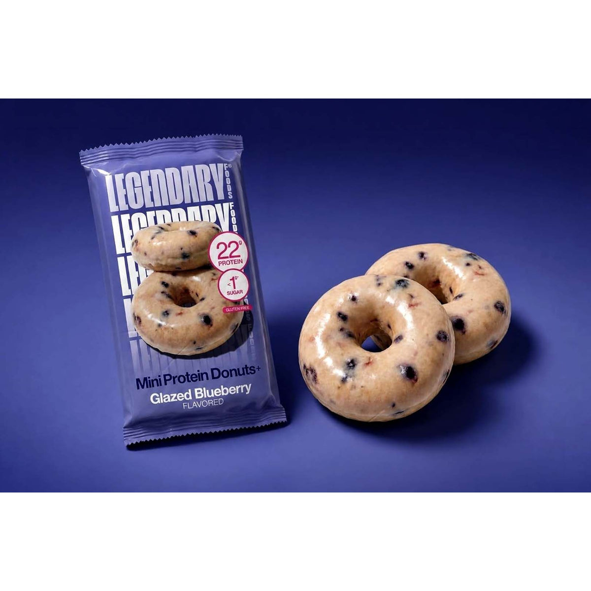 Legendary Glazed Blueberry Protein Donuts single pack beside two donuts on a blue backdrop
