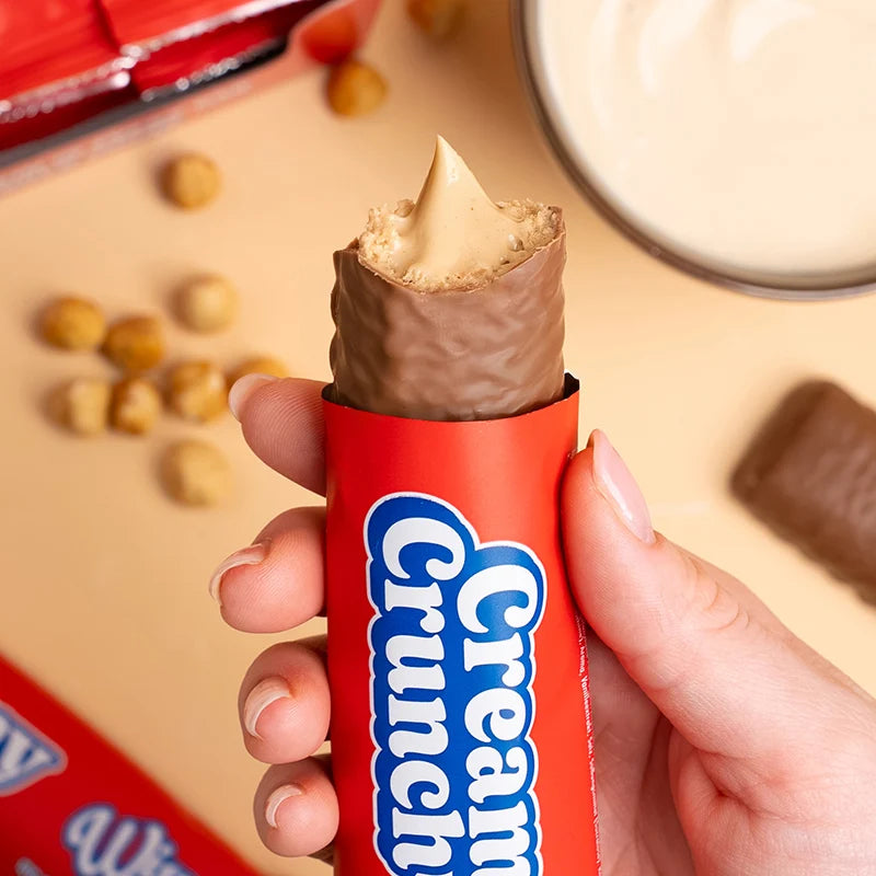 Wispy Creamy Crunch protein bar held in hand, red wrapper, 16g protein and no added sugar