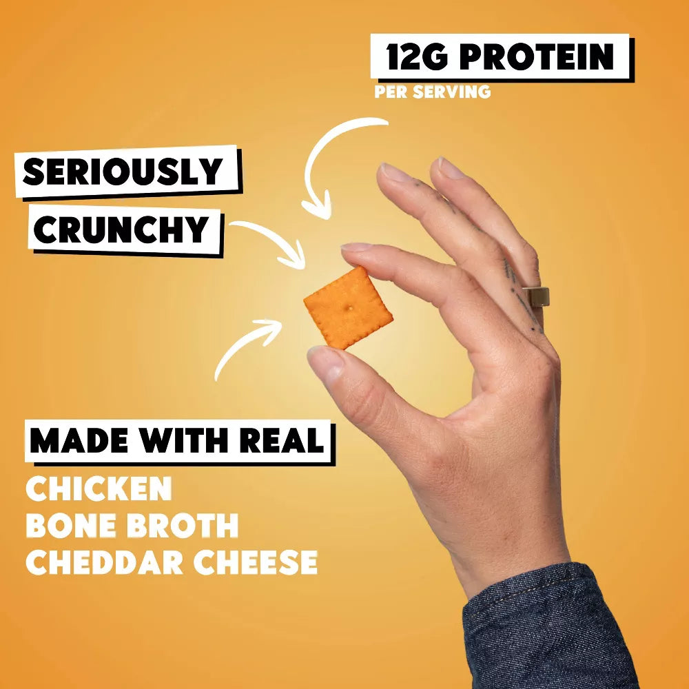 Hand holding one Wilde Classic Cheddar protein cracker, made with real cheddar, bone broth, 12g protein