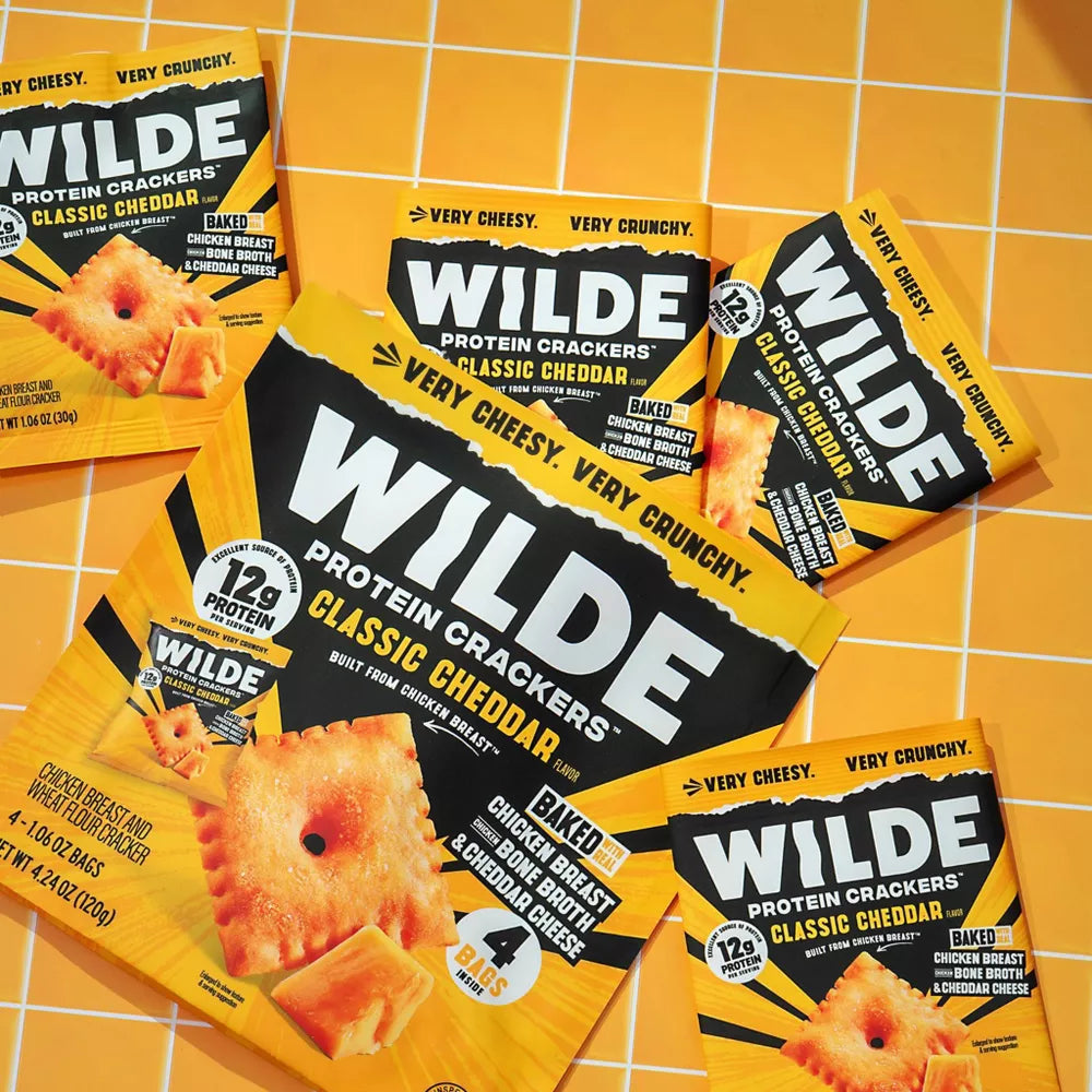 Wilde Classic Cheddar Protein Crackers single bags and 4-bag box flat-lay, made from chicken breast
