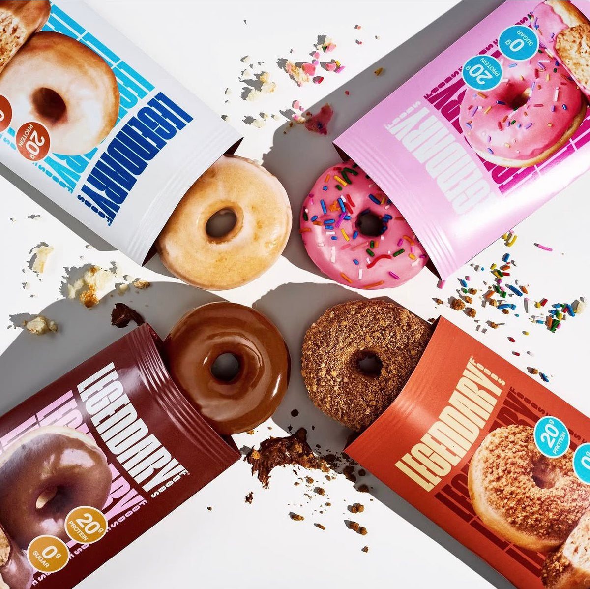 Overhead spread of Legendary Protein Donuts in every flavor with sprinkles and open packages