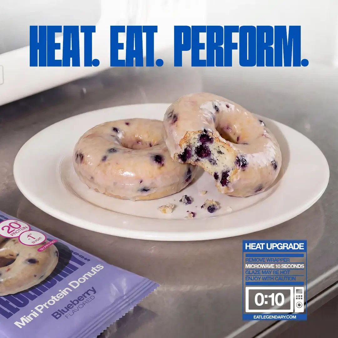 Two glazed Legendary Blueberry Protein Donuts on a white plate, warmed and ready to eat