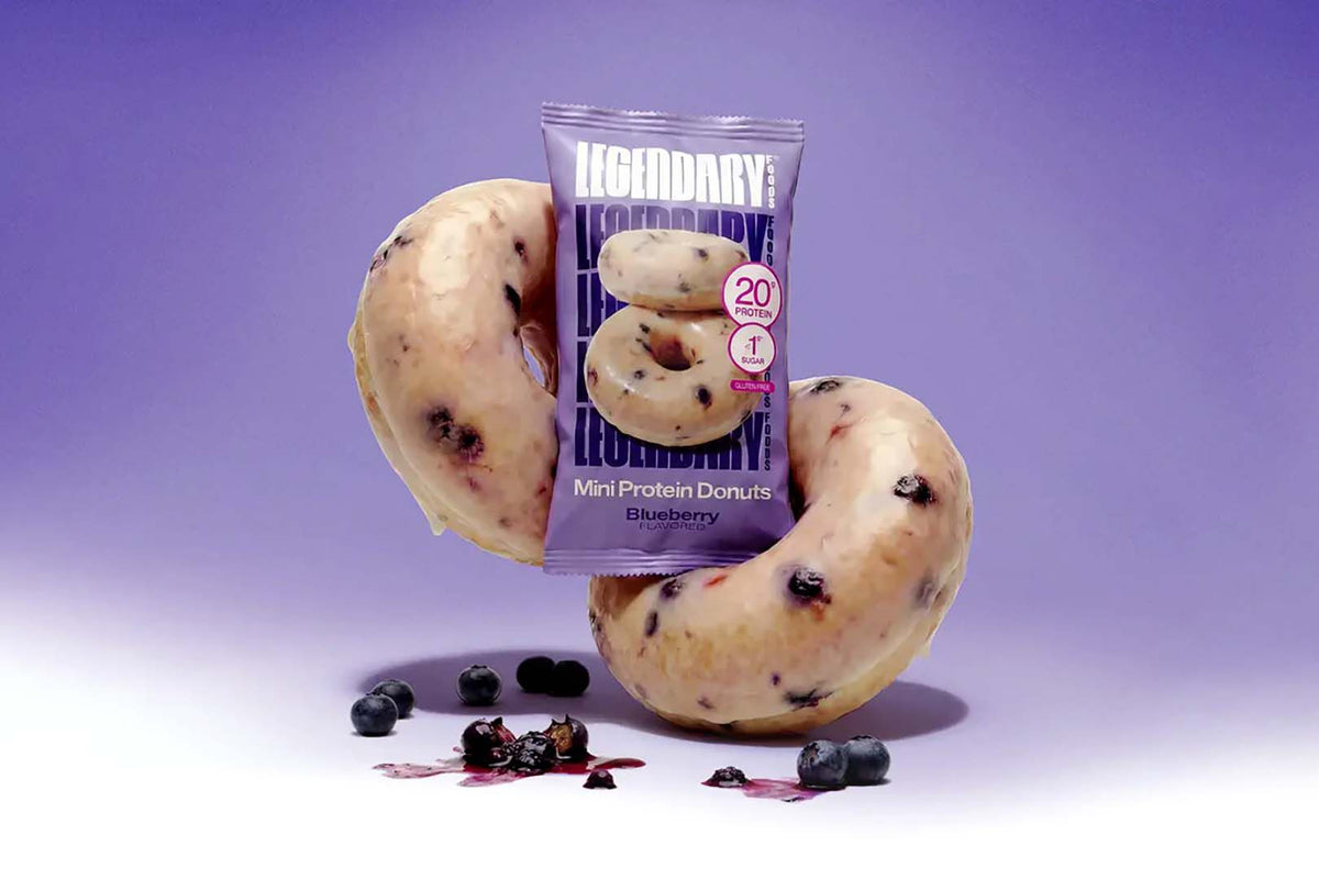 Legendary Blueberry Protein Donuts pack with two glazed donuts and fresh blueberries on purple