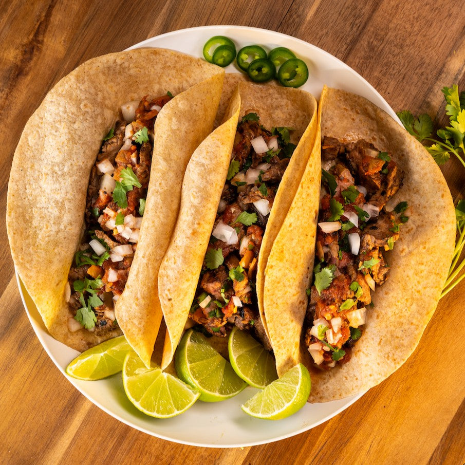 Joseph's Bakery Flax, Oat Bran & Whole Wheat Wraps folded as soft tacos with grilled meat, onion and lime on a plate