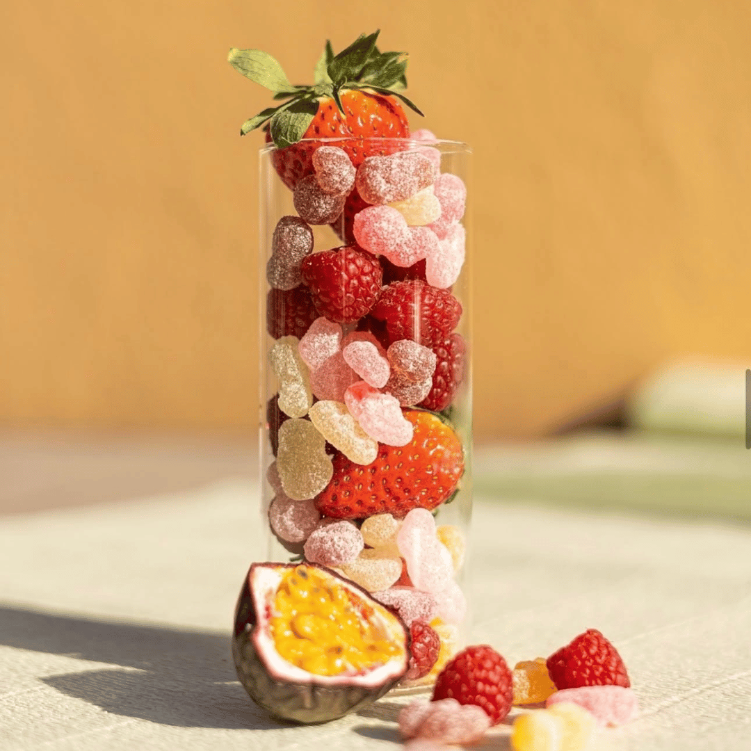 Wellibites Zero Sugar Vitamin Gummies served in a tall glass with fresh strawberries, raspberries and passion fruit